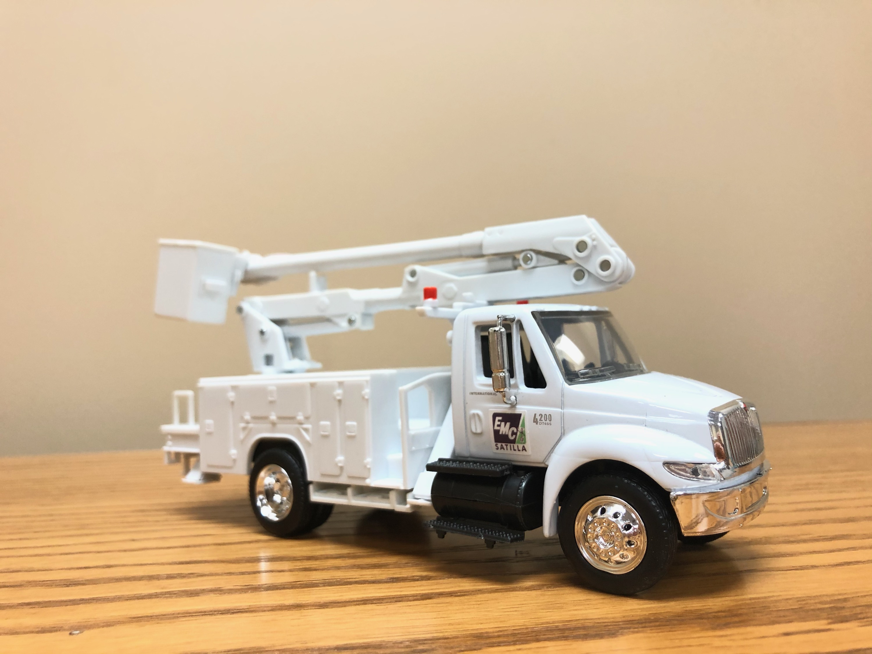 A small, white toy utilities truck with the Satilla EMC logo on it